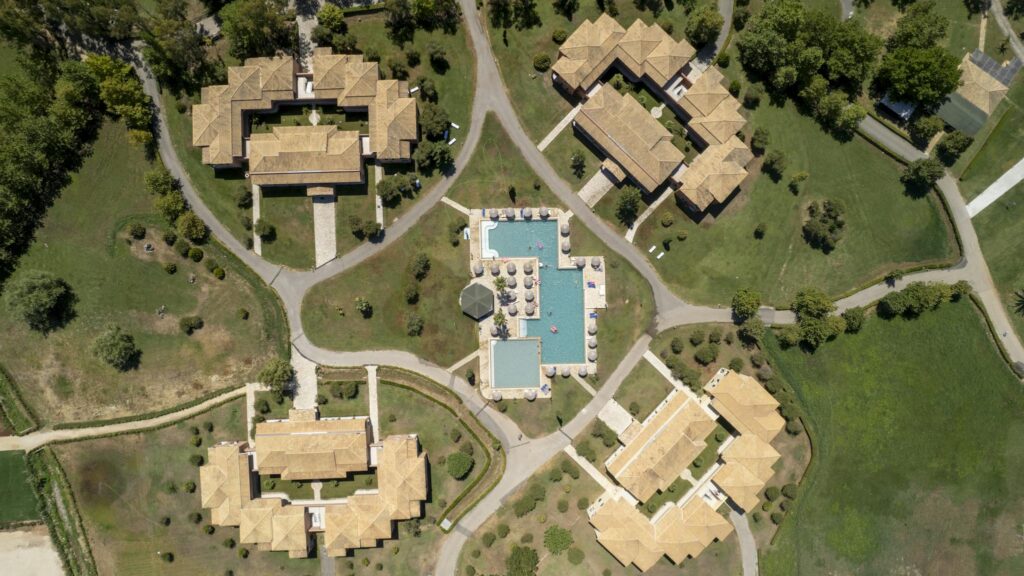 Aerial image showcasing resort villas and swimming pool in lush surroundings, Corfu, Greece.